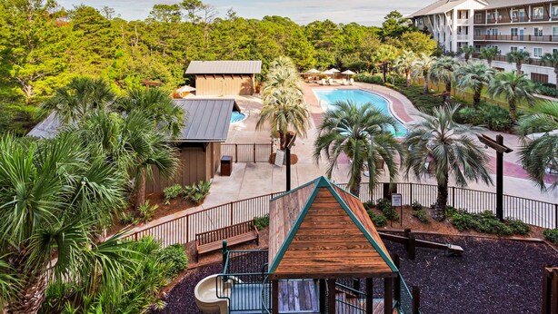 A resort with a pool, palm trees, and a building with a sloped roof. - Stunning condo with washer/dryer, pool & convenient beach access (Santa Rosa Beach)