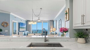 A kitchen with a large window, a ceiling fan, and a view of the ocean. - Enchanting oceanfront condo with pool, balcony, fitness area, & washer&dryer (Fort Walton Beach)
