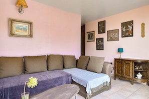 Una sala de estar con sofá, una mesita, un aparador y cuadros en la pared.
