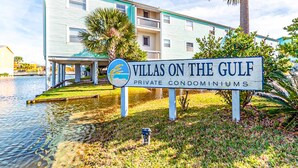 Une enseigne indiquant « Villas on the Gulf », signalant la présence de résidences privées avec vue sur l’eau, et un bâtiment visible au loin.