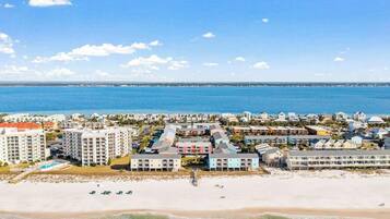A coastal hotel with multiple buildings, a beach, and a view of the sea.