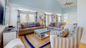 A spacious living room with two sofas, a coffee table, and a striped armchair. - Spacious home with  shared pool, large kitchen and close to beach (Pensacola Beach)