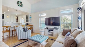 A spacious living room with a large flat-screen TV, a comfortable sofa, a striped armchair, and a wooden coffee table. - Spacious home with  shared pool, large kitchen and close to beach (Pensacola Beach)