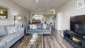 Ein modernes Wohnzimmer mit grauem Sofa, Couchtisch, TV-Schrank und Deckenventilator.