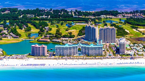 Ein Küstenhotel mit mehreren Hochhäusern, einem Strand und einem Golfplatz.