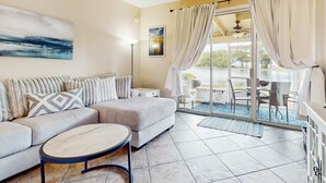 Una sala de estar moderna con un sofá, una mesa de centro y vistas a un balcón con mobiliario exterior.