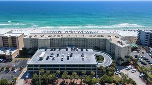 Een meerlaags hotel met een parkeerplaats en uitzicht op het strand.
