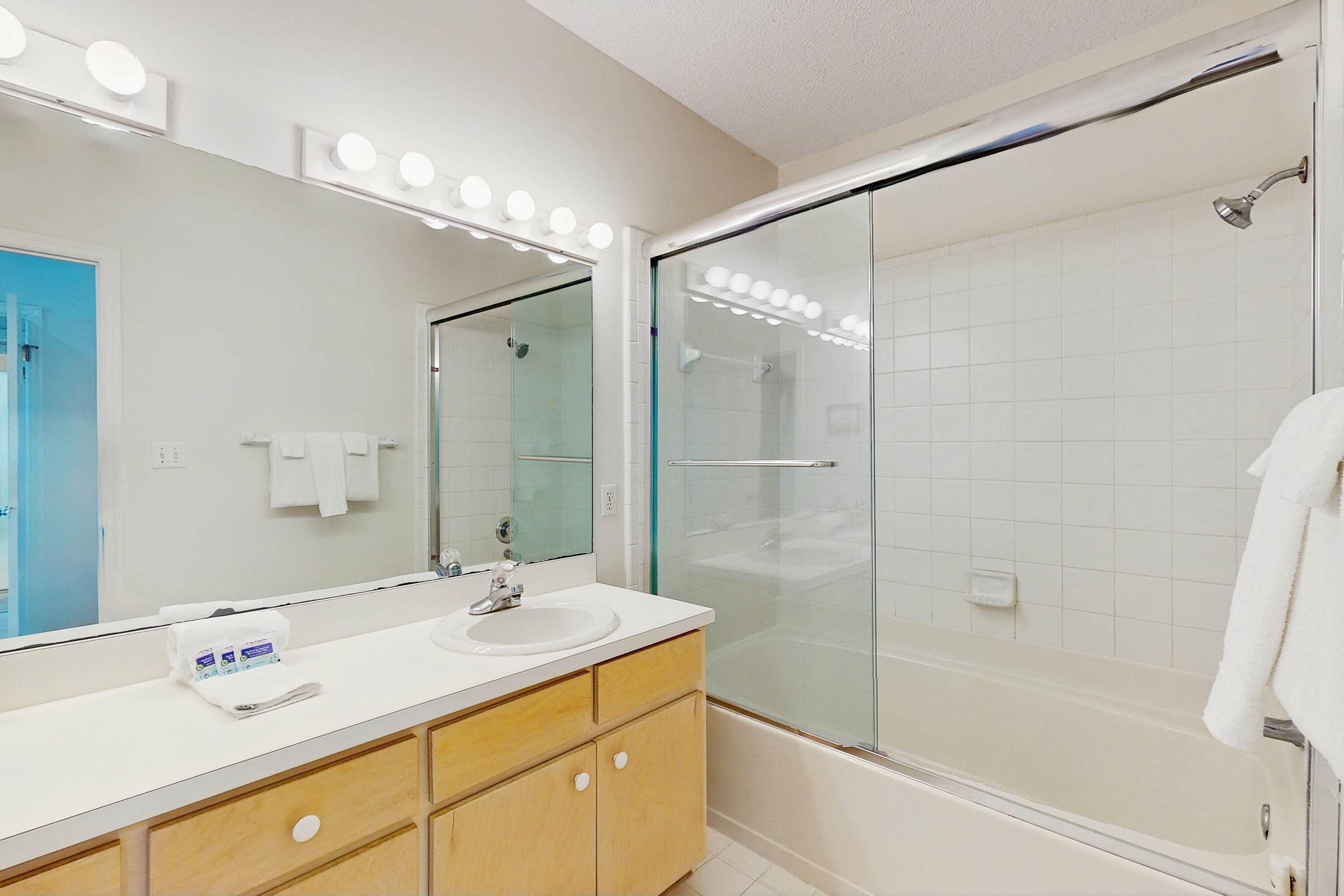 Un baño moderno con tocador, espejo y cabina de ducha de vidrio.