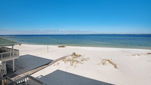 A beach view with a wooden deck and a building with a balcony.