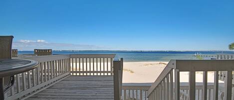 A wooden deck with a view of the beach and ocean.