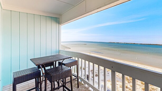 A covered outdoor area with a table and chairs, overlooking a beach.