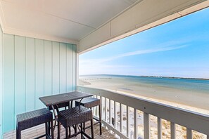 Un espace extérieur abrité, équipé d’une table et de chaises, donnant sur une plage.