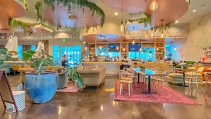 Un vestíbulo amplio con zona de bar, asientos y plantas en macetas.