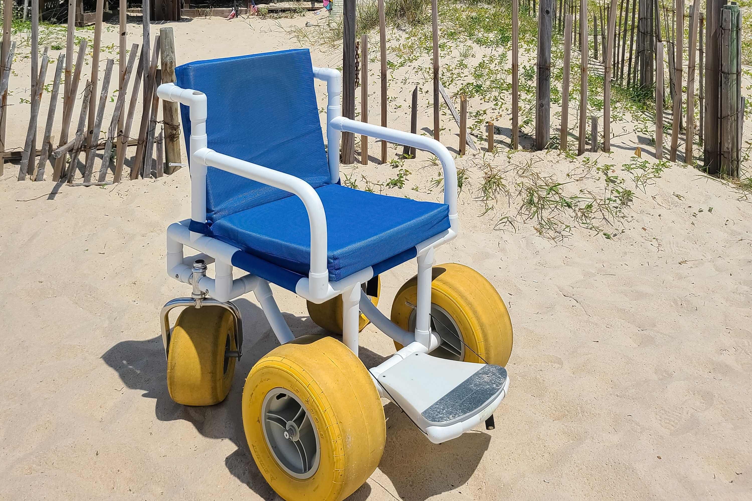 Una silla de ruedas en la playa, con detalles azules y amarillos.