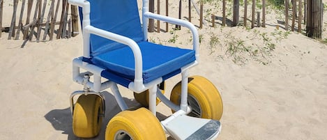 Una silla de ruedas en la playa, con detalles azules y amarillos.