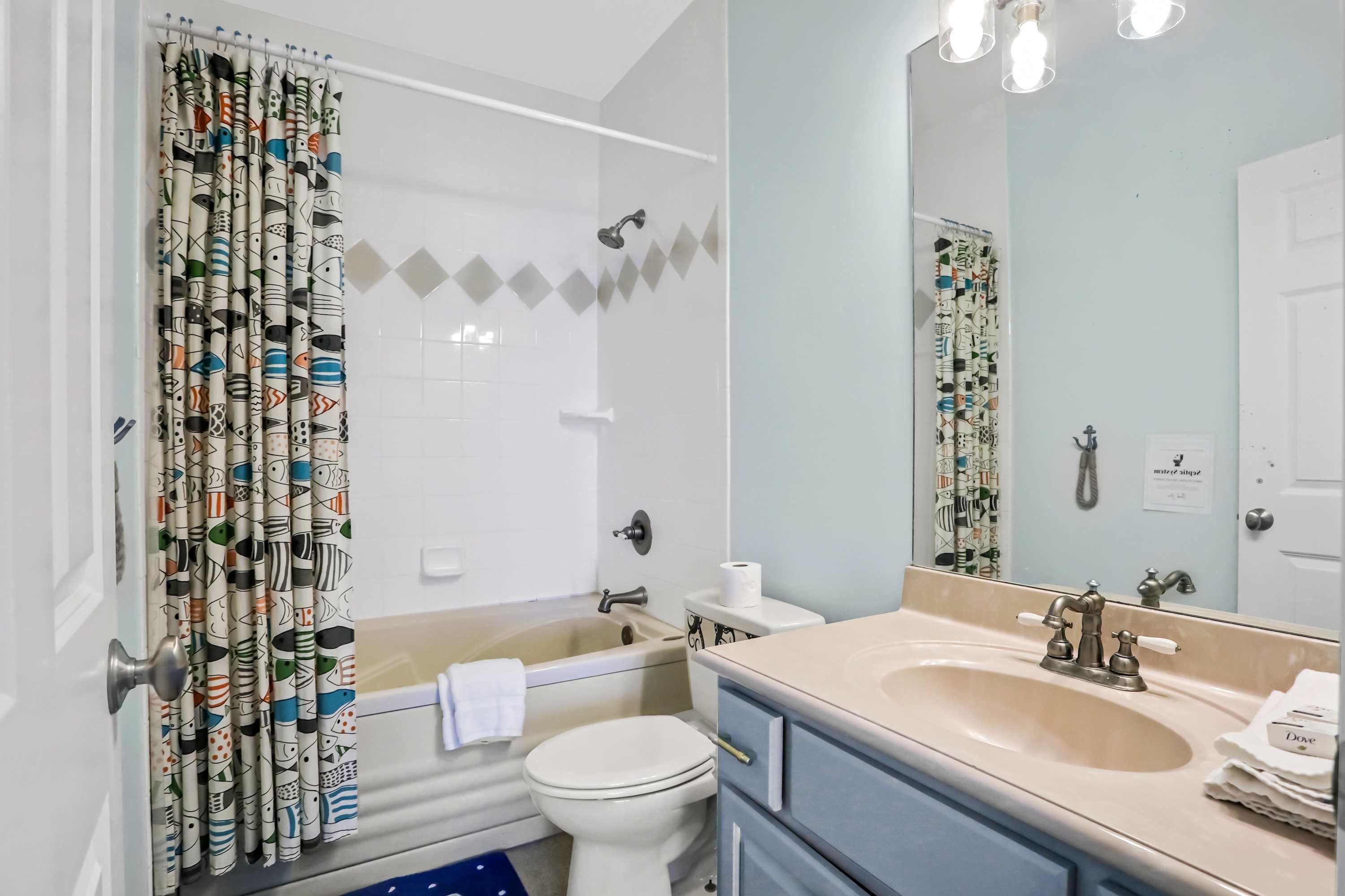 Baño con ducha, inodoro, lavabo y espejo.
