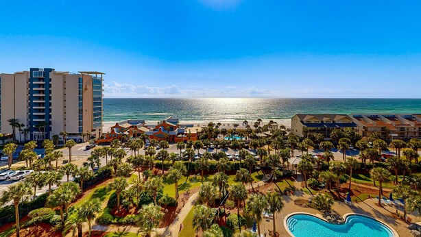 Ein Resort mit Pool, Palmen und Blick auf den Ozean.