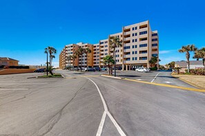 Un hotel de varios pisos con estacionamiento y palmeras.