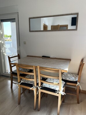 A dining area with a wooden table and chairs, a mirror on the wall, and a sliding glass door leading outside. - Apartment Lavaran 3 in Vir (Vir)