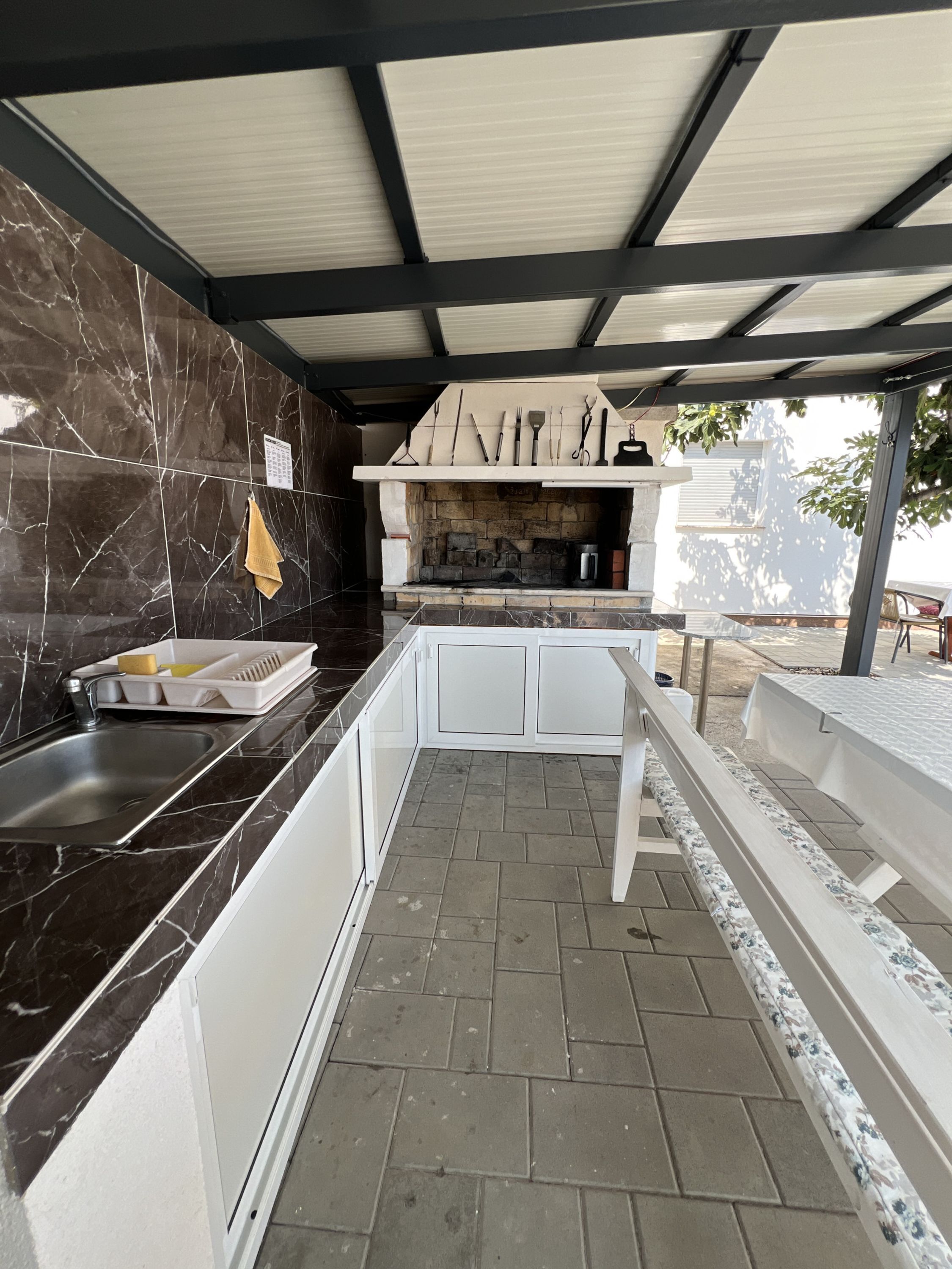 A kitchen with a stone backsplash, a built-in oven, and a dining area with a bench. - Apartment Lavaran 3 in Vir (Vir)
