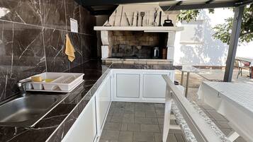 A kitchen with a stone backsplash, a built-in oven, and a dining area with a bench.