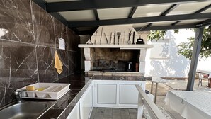 A kitchen with a stone backsplash, a built-in oven, and a dining area with a bench. - Apartment Lavaran 4 in Vir (Vir)