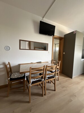 A dining area with a wooden table and chairs, a flat-screen TV mounted on the wall, a mirror above the table, and a refrigerator in the background. - Apartment Lavaran 4 in Vir (Vir)