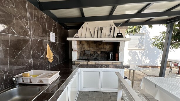 Una cocina con salpicadero de piedra, horno empotrado y zona de comedor con banco.