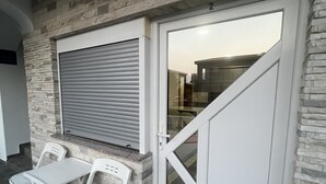 Una habitación con pared de piedra, una puerta corredera cerrada y dos sillas blancas.
