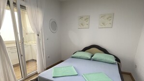Een slaapkamer met een bed, een glazen schuifdeur en een kleine ronde spiegel aan de muur.