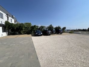 A parking area with four cars parked in a row, a gravel surface, and a paved walkway. - Apartment Lavaran 5 in Vir (Vir)