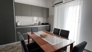 A modern kitchen with grey cabinets, a wooden dining table, and black chairs. - Apartment Lavaran 6 in Vir (Vir)