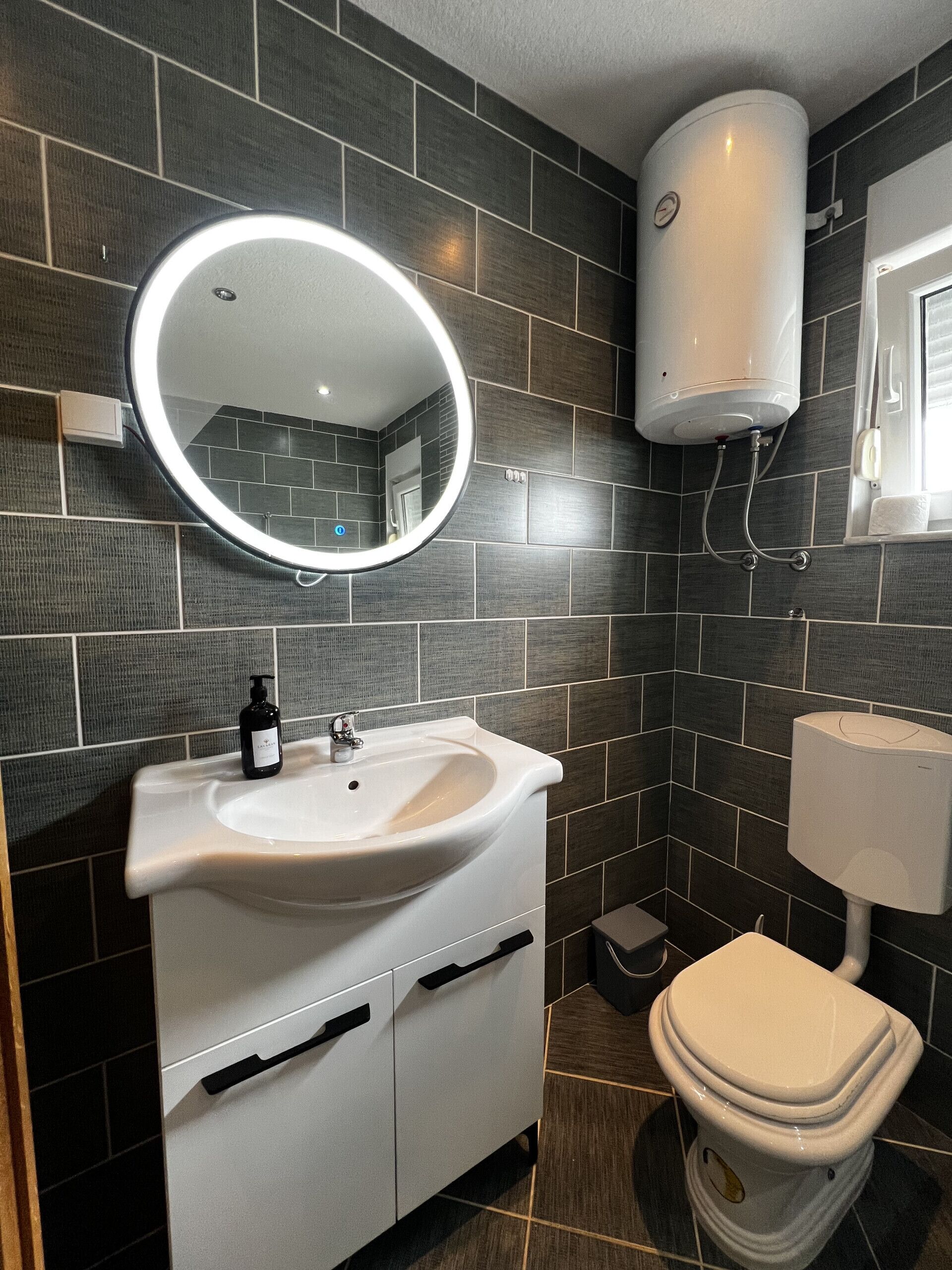 Et moderne badeværelse med vask, spejl og toilet.