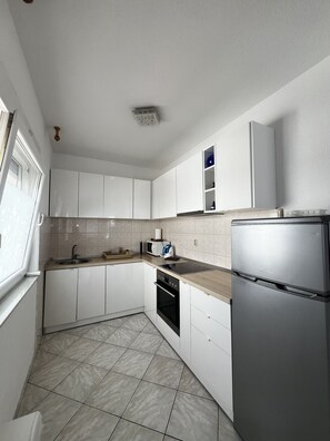 A modern kitchen with white cabinets, a stainless steel refrigerator, a built-in oven, and a microwave. - Apartment Lavaran 1 in Vir (Vir)