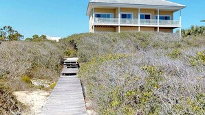 Una casa sul lungomare con un terrazza in legno che conduce a un balcone.