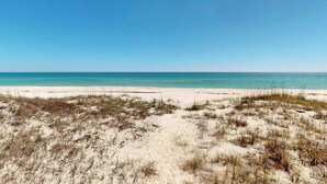 Una spiaggia con dune di sabbia e un cielo azzurro limpido.