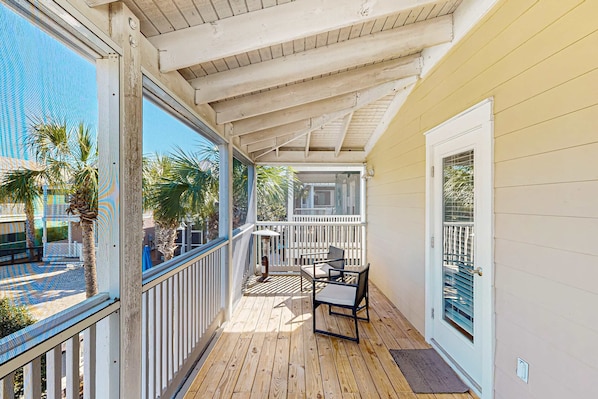 A wooden deck with a white railing, a door with a window, and a small table and chair. - Dog-friendly 2BR home with screened porch, pool, & hot tub - beach access one mile away - snowbirds welcome (Port St. Joe)