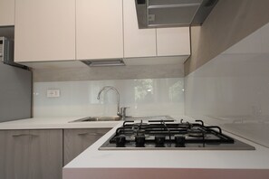 A modern kitchen with white cabinets, a stainless steel sink, and a gas stove. - Rosolina Apartment With Parking (Rosolina)