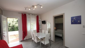 Ein modernes Zimmer mit einem weißen Tisch und Stühlen, einem Bett und einem Fernseher.