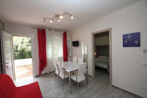 A modern room with a white table and chairs, a bed, and a TV. - Rosolina Apartment With Parking (Rosolina)