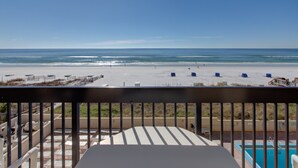 Een balkon met uitzicht op een strand en een zwembad.