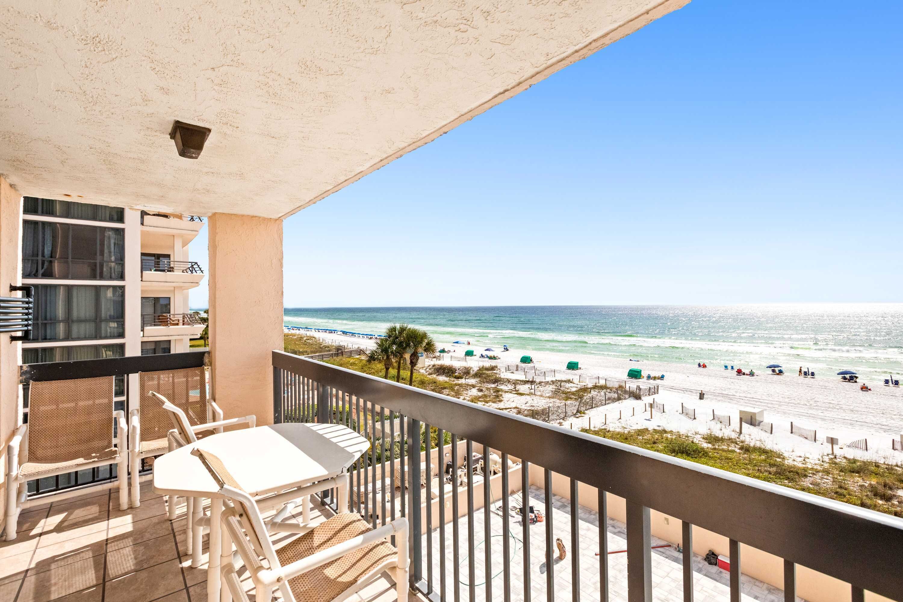 A balcony with a view of the beach and ocean.