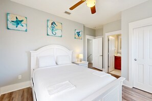 A bedroom with a large bed, a ceiling fan, and artwork on the wall. - 2-story beach cottage with pools, hot tub, gym, patio, & AC - dog-friendly (Port St. Joe)