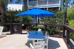 An outdoor patio with a blue umbrella, white chairs, and a table. - 2-story beach cottage with pools, hot tub, gym, patio, & AC - dog-friendly (Port St. Joe)