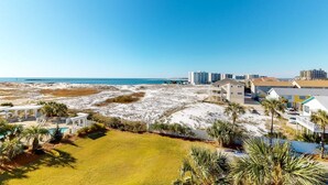 En fastighet vid kusten med pool, utsikt över stranden och flera byggnader.