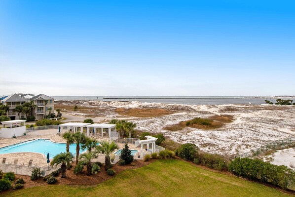 A beachfront property with a swimming pool, multiple guest villas, and a view of the ocean. - Magnolia House at Destin Pointe 412 (Destin)