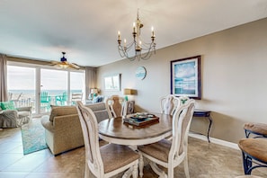 A dining area with a round table, white chairs, and a chandelier. - Gorgeous, beachfront condo with view of the gulf plus a pool (Destin)
