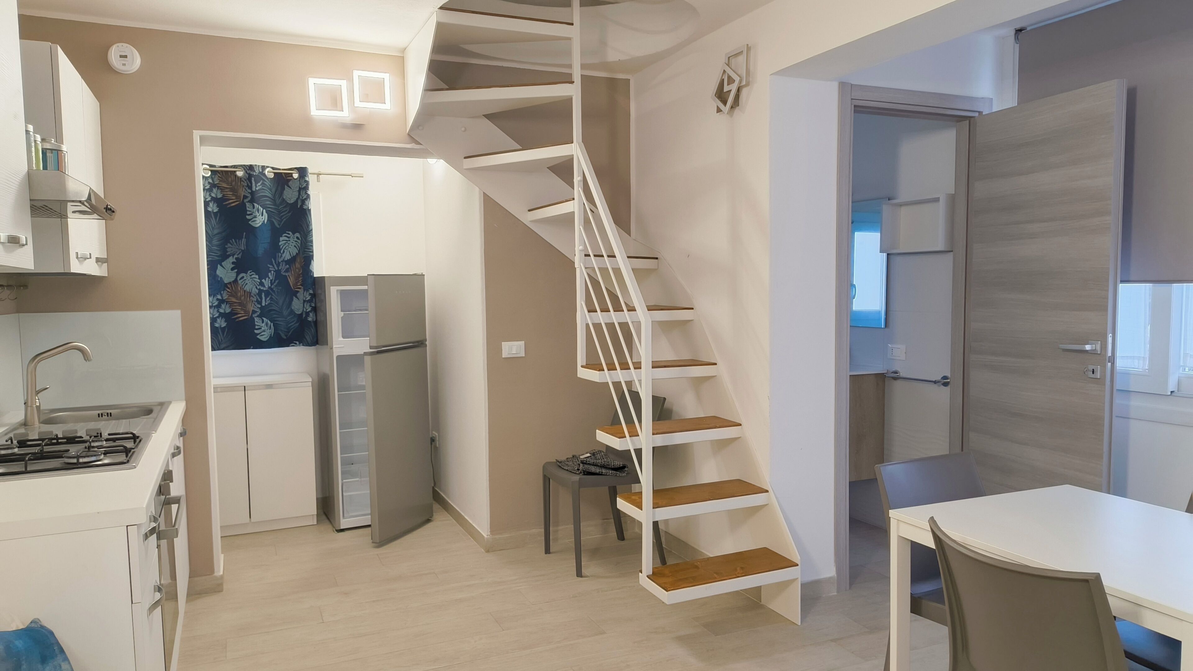 Una cocina compacta con estufa a gas, refrigerador y zona de comedor con mesa y sillas.