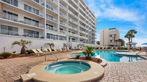 A hotel with multiple floors, outdoor swimming pool, and lounge chairs. - Seaside escape with water view, balcony, pool, pool spa & gym access (Destin)