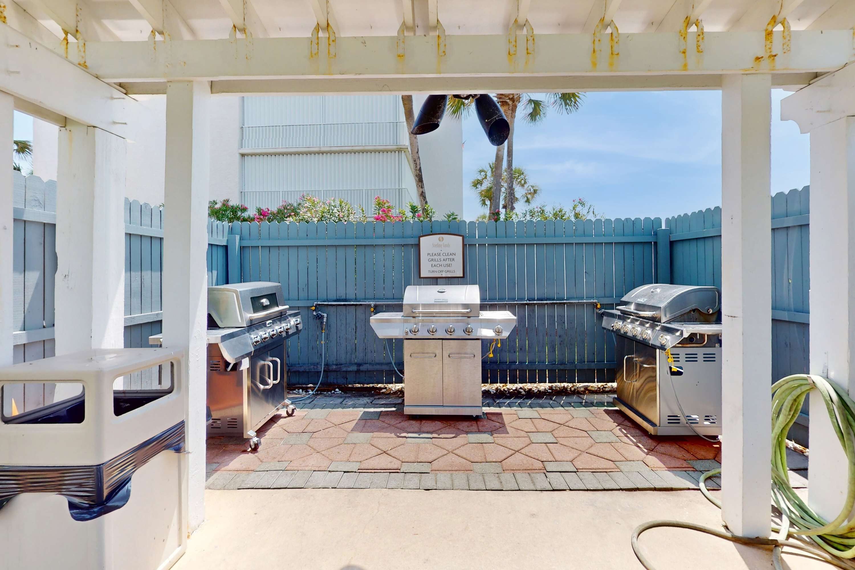 An outdoor barbecue area with a grill, a grill cover, and a hose.